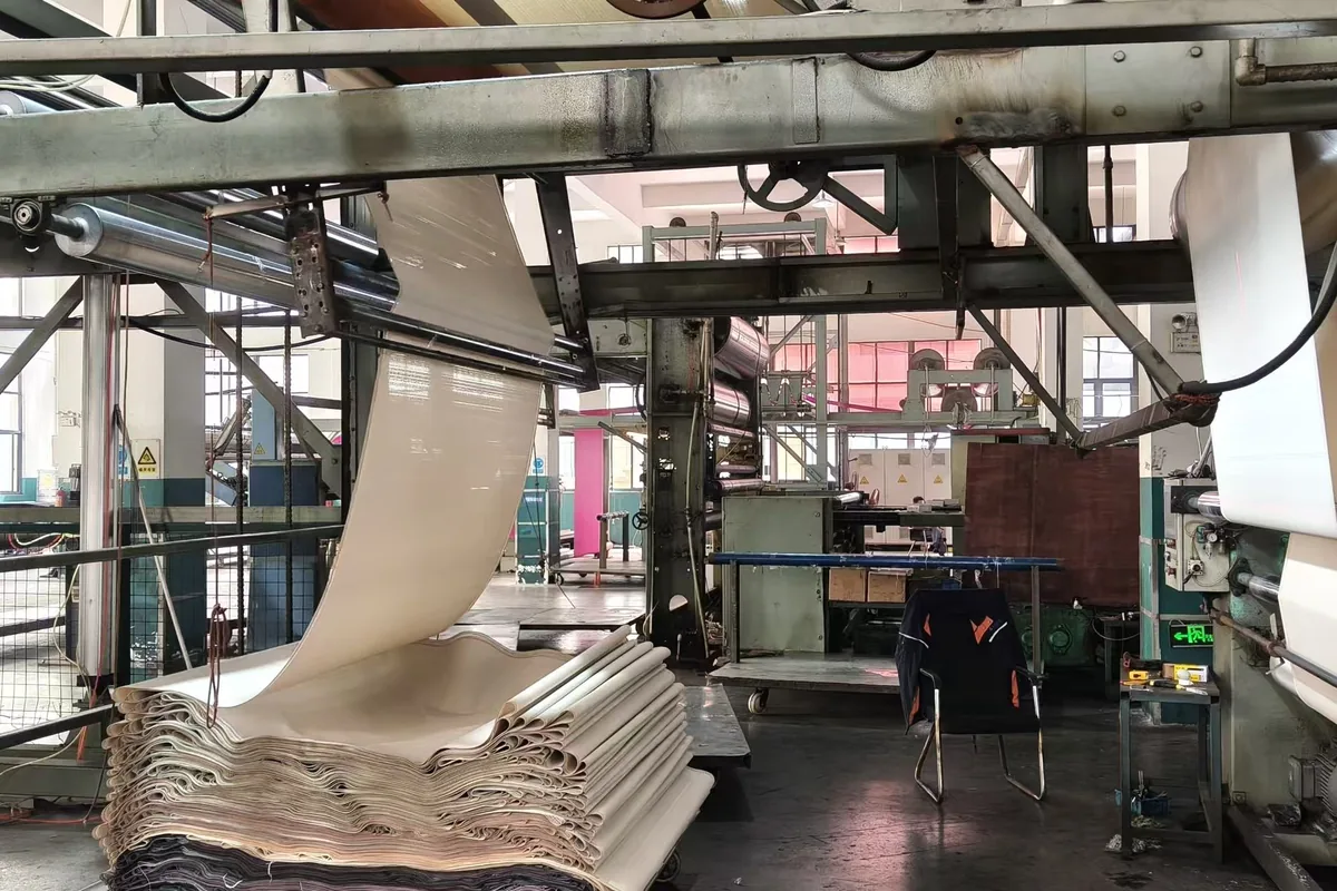 Finishing at the woven vinyl production base in Zhejiang: the roll running through the line, with finished lengths stacked