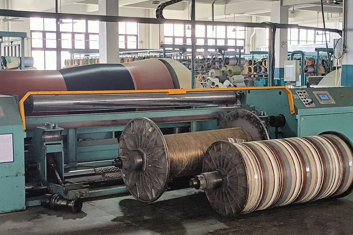 Warping at the woven vinyl production base in Zhejiang: the coloured warp wound onto the beam, with warp beams in front